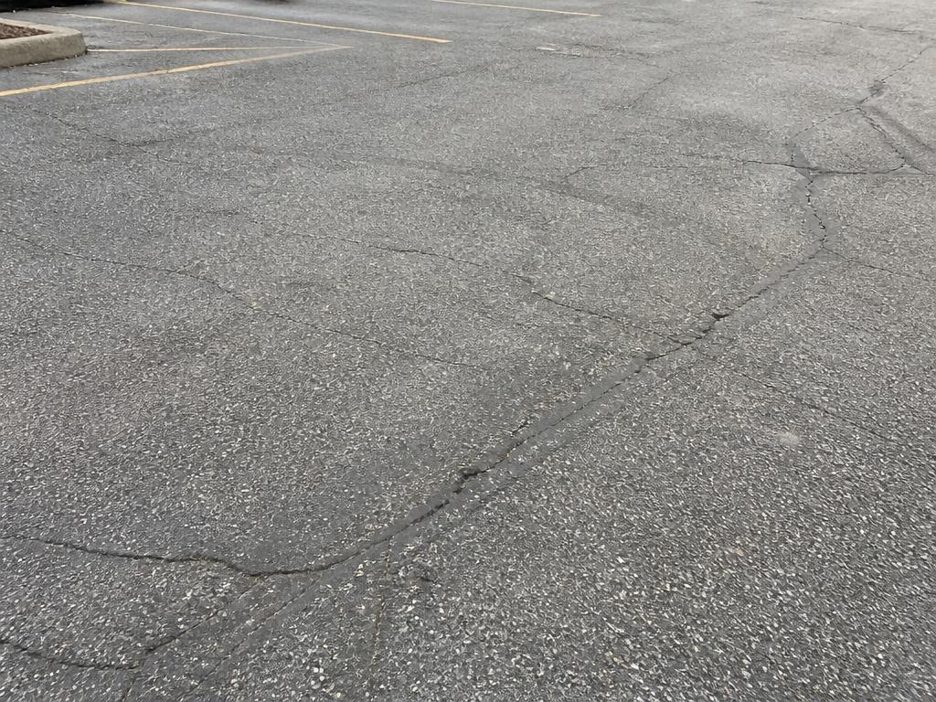 Gray oxidized asphalt surface with cracks before sealcoating